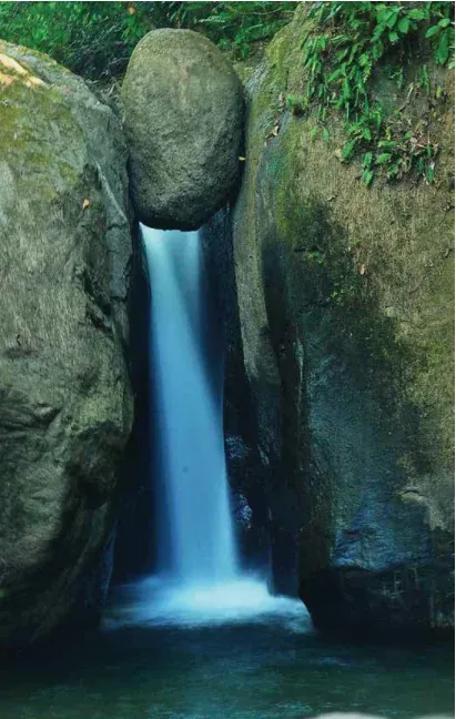 El Pavón waterfall in Ojochal, with a round boulder wedged at the top of the fall