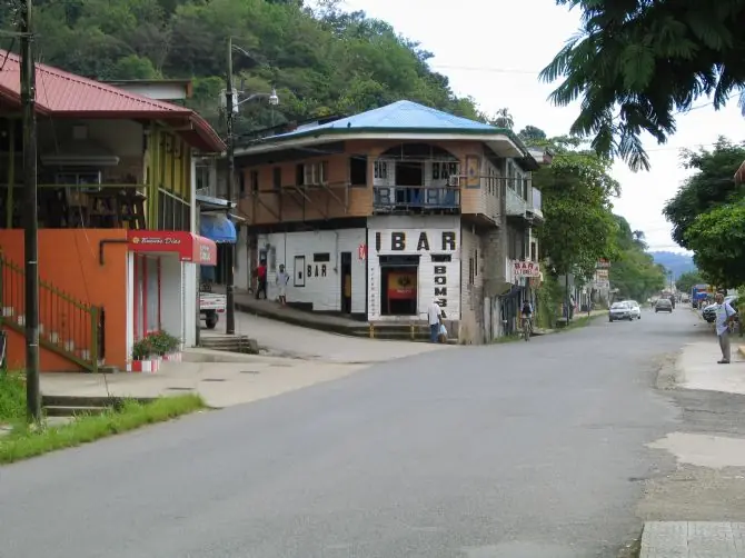 A street in Golfito with wooden two-story buildings and green hills behind