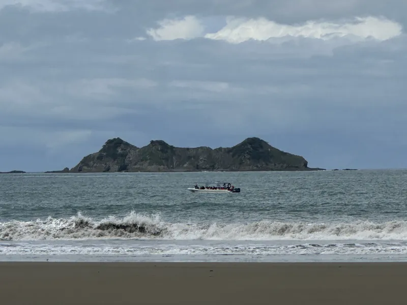 A boat passes a rocky island off the Pacific coast