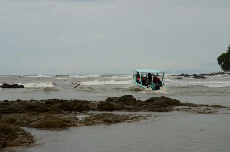 A tour boat landing on the rocky shore of the Osa Peninsula near Drake Bay