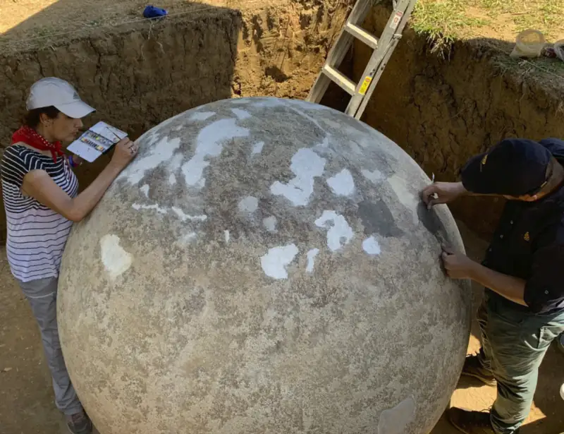 Conservadores del Museo Nacional restaurando una esfera de piedra grande en una excavación de Finca 6